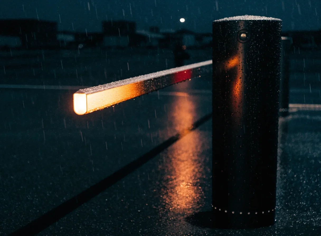 A wet parking entry boom and unlit scanner surface at a Melbourne Airport car park at night